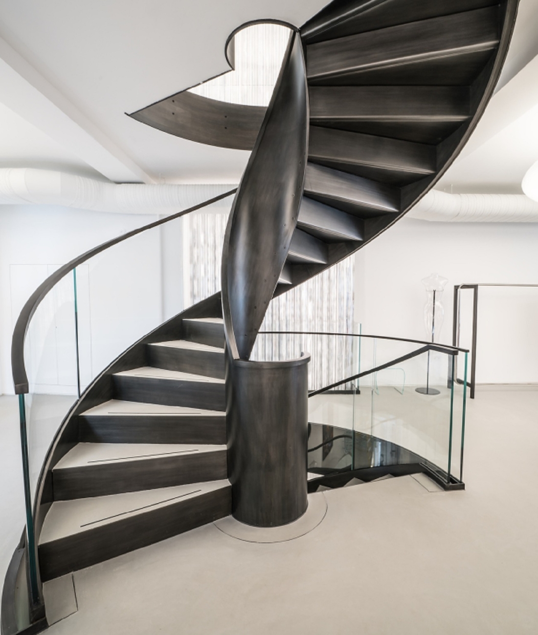 Scala elicoidale in acciaio realizzata da Pifferi & Alpi a Londra, struttura scultorea con parapetto in vetro e finitura metallica acidata.