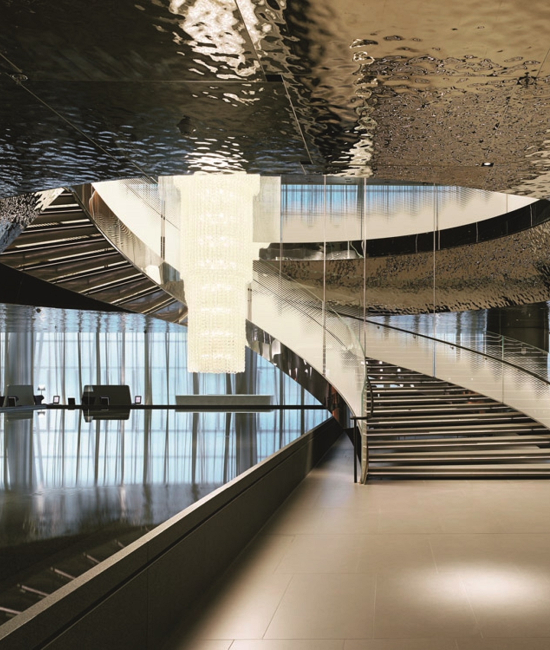 Scala monumentale in acciaio e vetro realizzata da Pifferi & Alpi, struttura elicoidale di design contemporaneo con finiture lucide e dettagli architettonici di pregio.