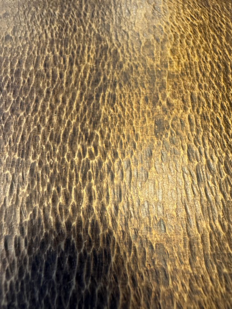 Superficie in ottone lavorata con tecnica di martellatura, che genera una texture irregolare e vibrante ricca di riflessi. Una finitura dal carattere artigianale e distintivo, ideale per elementi decorativi, pannelli e arredi di design che richiedono un forte impatto materico.